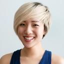 A smiling young Asian woman with short, bright blonde hair and a dark top.